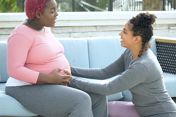 woman with her hands on a pregnant woman's stomach