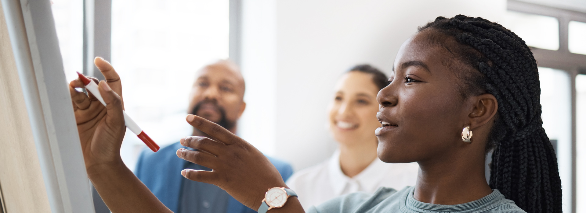 woman presenting to colleagues on a whiteboard